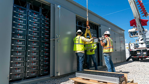 three workers building a battery storage unit
