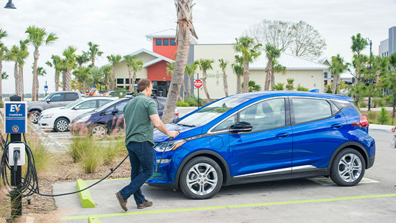 a man charging his electric vehicle at a charging station in innovation way, babcock ranch