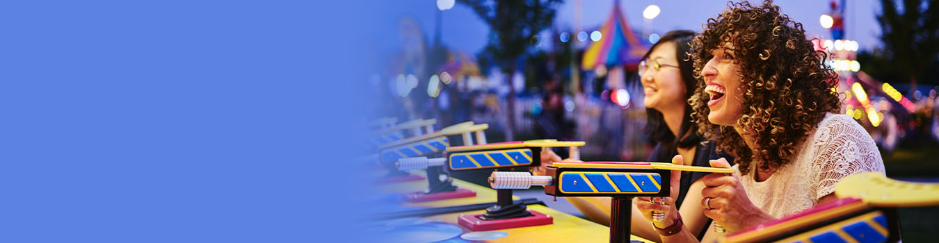 two women having fun playing a game in the evening at an amusement park