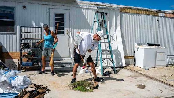 woman and man cleaning up debris after hurricane ian