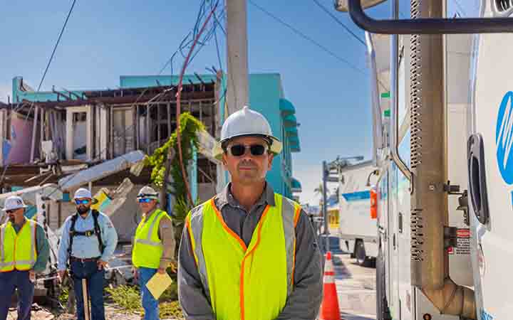 image of man standing amid hurricane restoration efforts