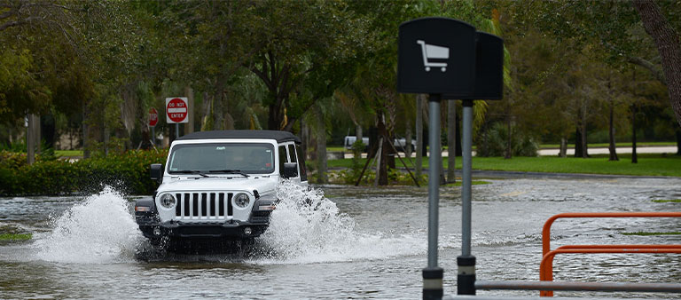 a vehicle driving through a flooded parking lot