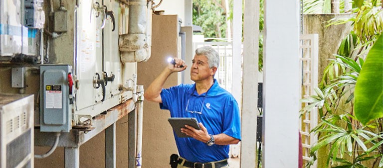 an energy expert assessing an AC unit holding a flashlight