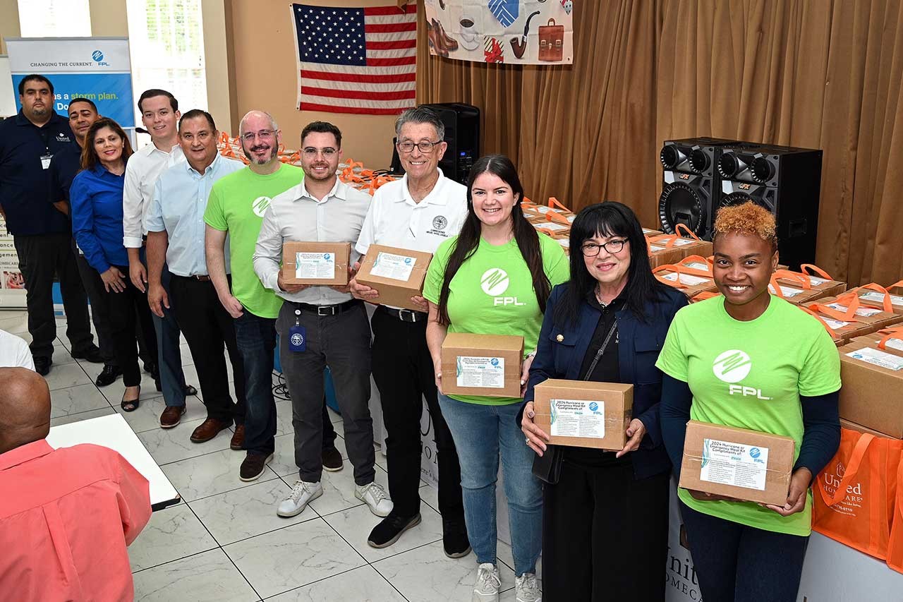 FPL employees holding hurricane meal kits and smiling.