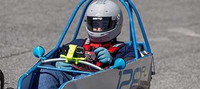 Person driving an electric go-cart with helmet