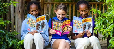 Three girls sitting on a porch reading 