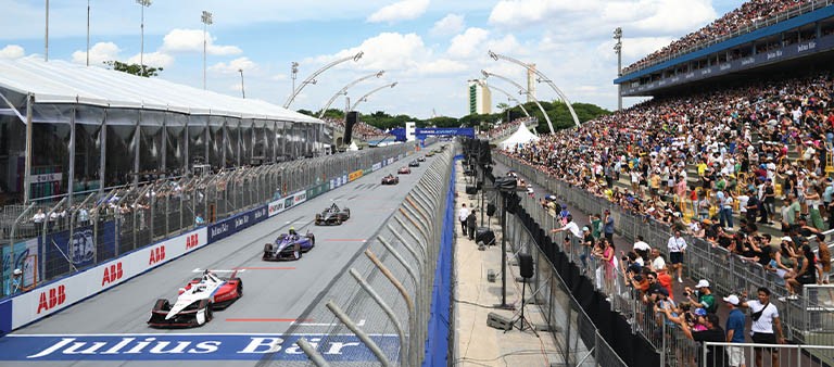 racecars crossing a finish line on a racetrack at a stadium