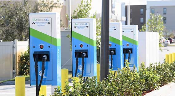 row of parked fpl vehicles by fpl electric vehicle chargers