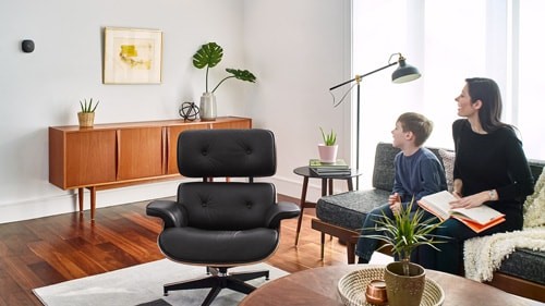 Mother and son sitting on a couch looking over at the ecobee smart thermometer on the wall