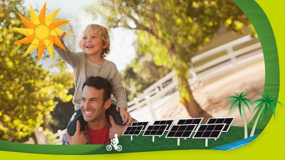 Niño sobre los hombros de su padre frente a un parque de paneles solares