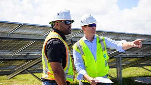two fpl workers talking on a solar field