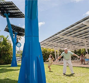 A dad and daughter playing in a park underneath solar trees