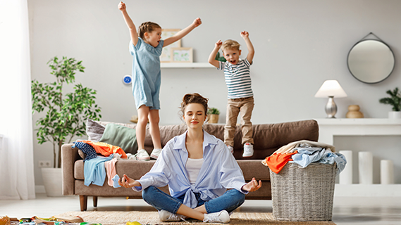 woman in yoga pose with children jumping in background