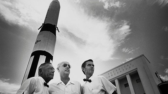 worms eye view of a three men at Cape Canaveral standing in front of a space ship 