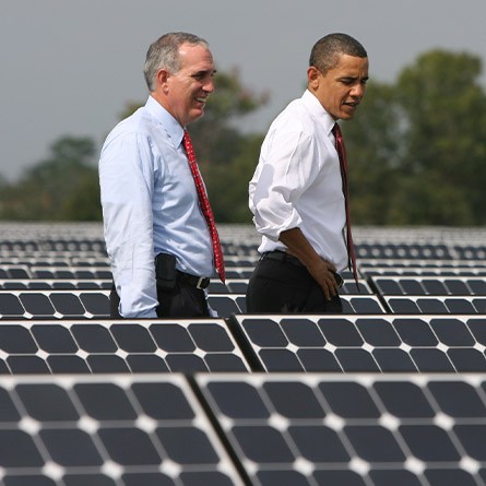 Lew Hey and Barack Obama walking through a solar panel field