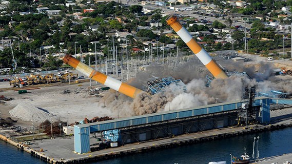 drone aerial view of the Riviera plant demolition - two plant towers coming down surrounding by dust and debris