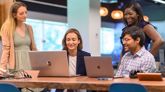 a group of employees at their laptops having a discussion
