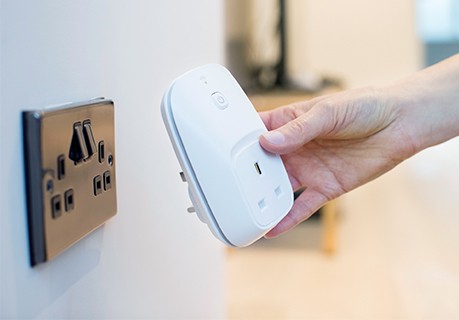 A hand holding a smart plug