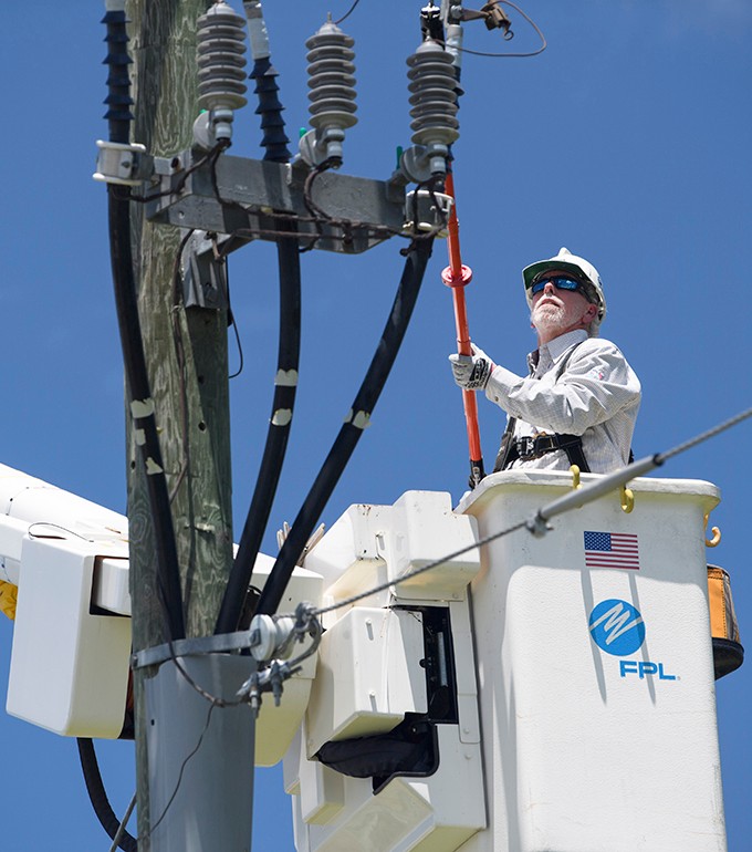 two fpl linemen in a bucket truck assessing a powerline