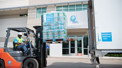 FPL employee putting cases of water bottles on a truck