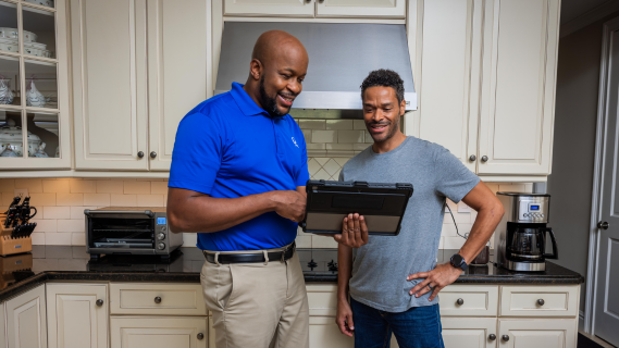 two men in kitchen looking at device