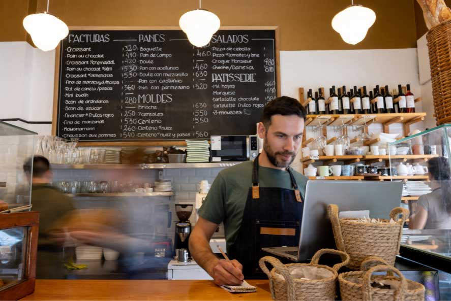 man wearing an apron behind a coffee shop counter