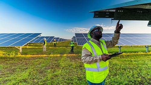 a worker in a safety vest examining a solar panel