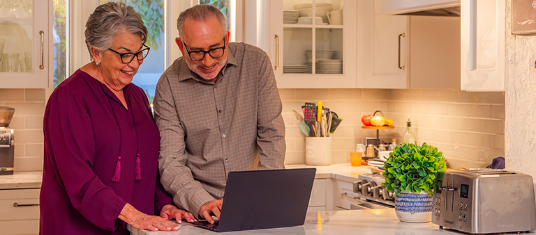older couple looking at computer screen in kitchen