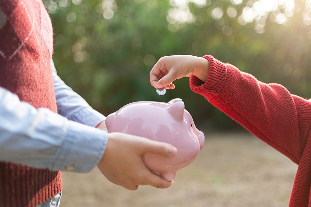 child putting coins in the piggy bank