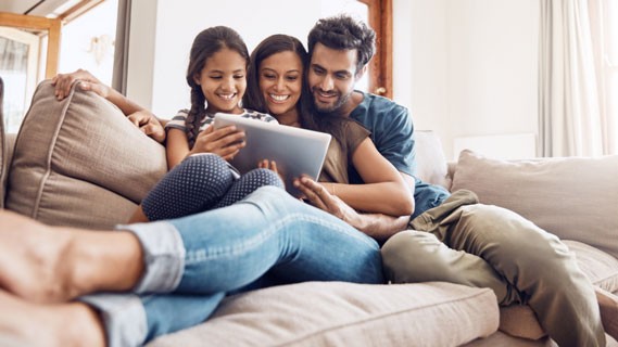 Family on a couch smiling at a tablet 
