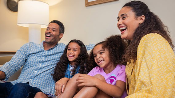 a family of four sitting on a couch laughing together