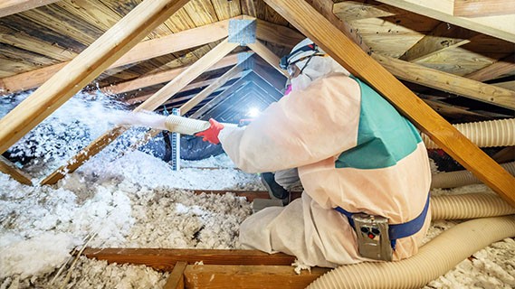 a contractor filling ceiling space with insulation