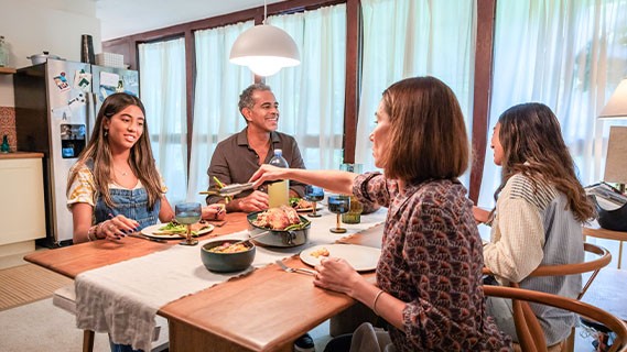 a family of four having dinner together at their dining table in the kitchen