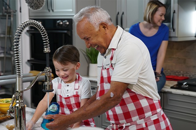 a child and his grandpa cooking together