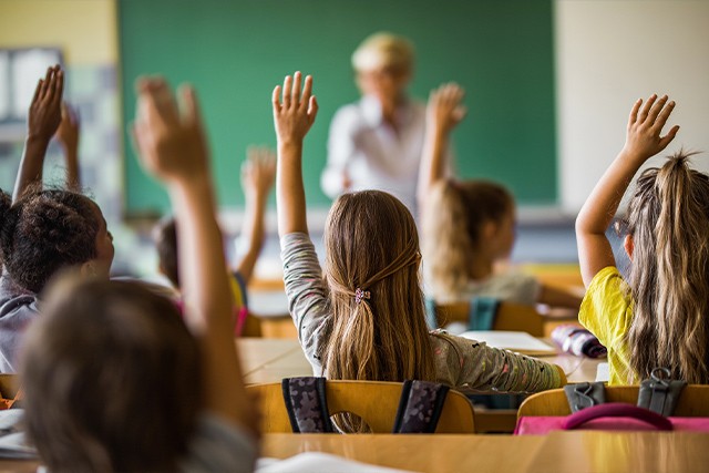 a classroom with students raising their hands