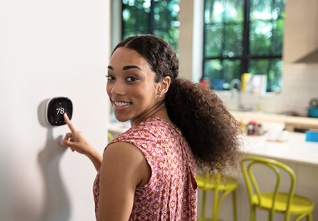 woman at home raising thermostat to 78
