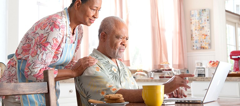 Man and woman at kitchen table looking at computer screen