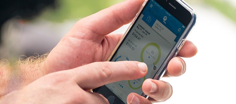 Hand holding mobile device showing FPL app