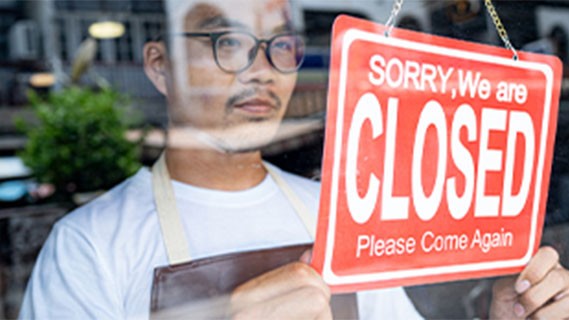 business owner holding closed sign