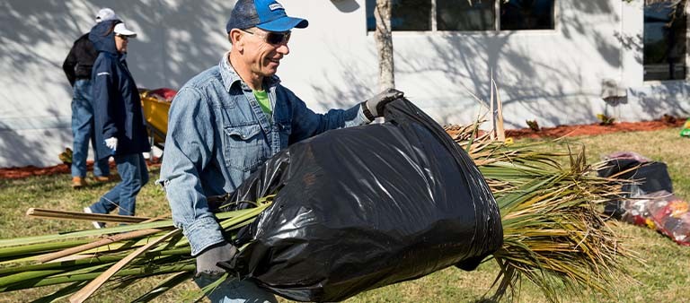 a man carrying a bag with tree leaves