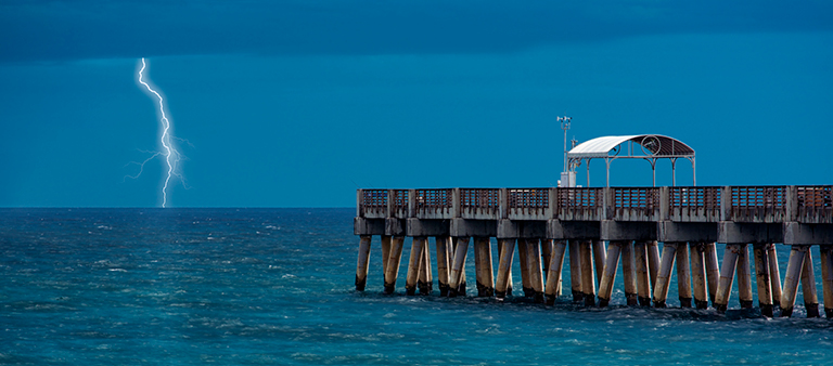 lightning striking near pier in stormy weather