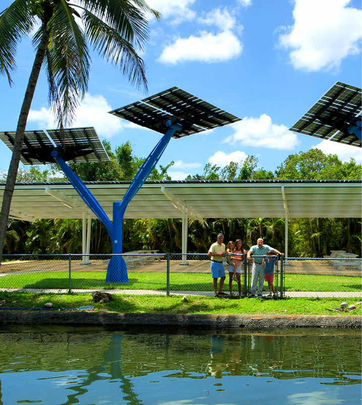 family sitting down at picnic tables under a solar canopy